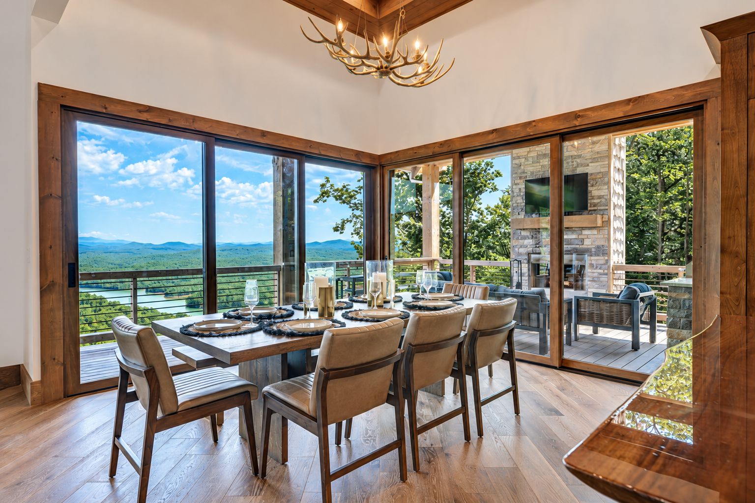 A spacious dining area with a table set for six, large windows offering a view of the outdoors, and a stone fireplace.