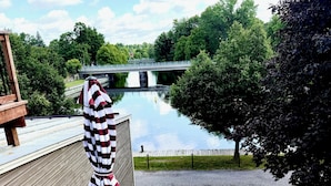 Une terrasse avec une table et des chaises, donnant sur une rivière et un pont.