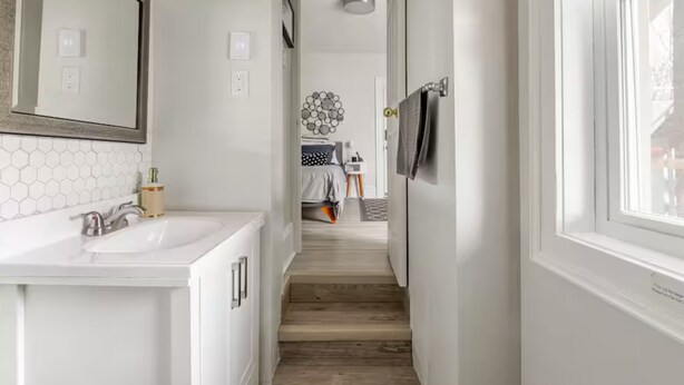 Un couloir étroit avec un escalier en bois menant à une chambre.