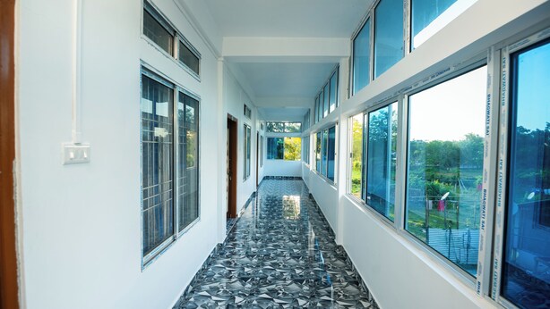 A corridor with large windows and a tiled floor. - Jungle Star Mansion (Bokakhat)