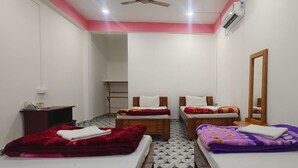 A small, clean room with two beds, a mirror, and a ceiling fan. - Jungle Star Mansion (Bokakhat)