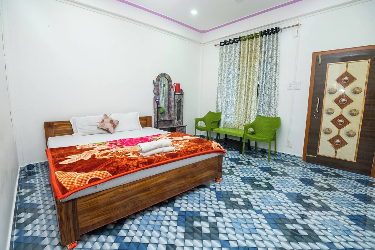 A neatly arranged bedroom with a wooden bed, a green chair, and a patterned floor.