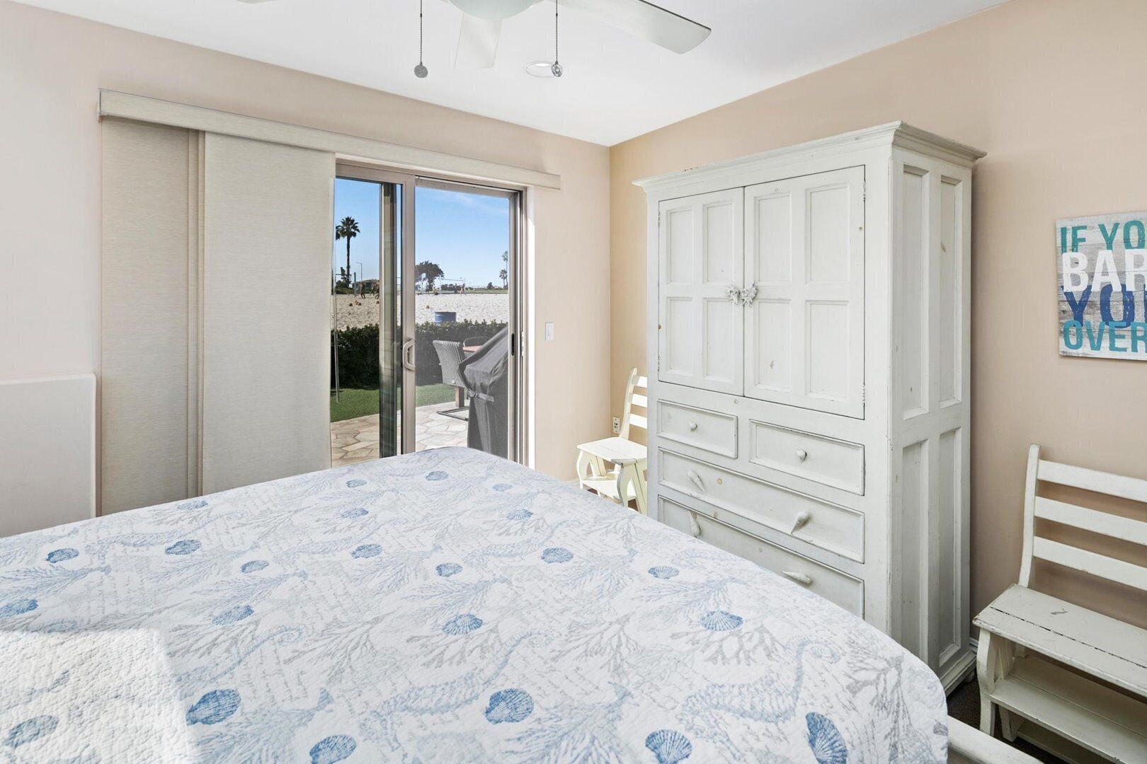 A bedroom with a bed, a wardrobe, a chair, and a view of the outdoors.