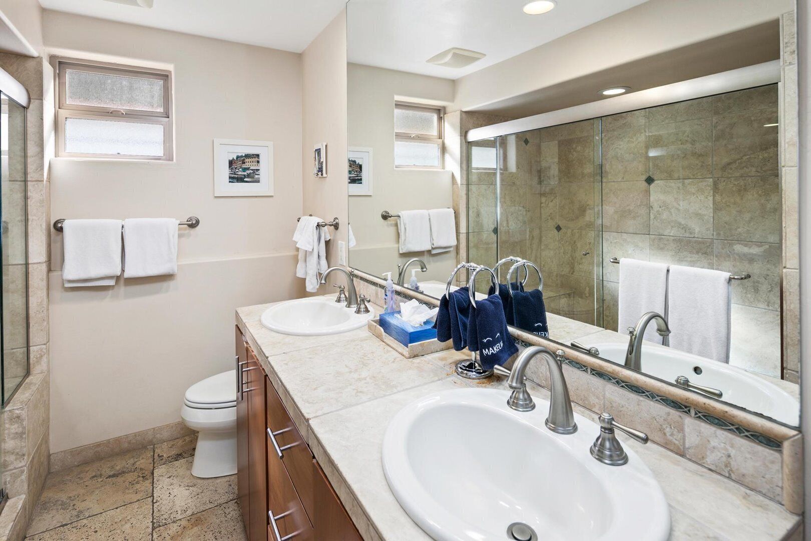 Un baño moderno con dos lavamanos, un inodoro y un espejo grande.