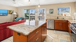 A modern kitchen with a granite countertop, wooden cabinets, and a dishwasher. - Three Bedroom on the Ocean Front! (San Diego)