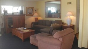 A living room with a sofa, a coffee table, a lamp, and a mirror.
