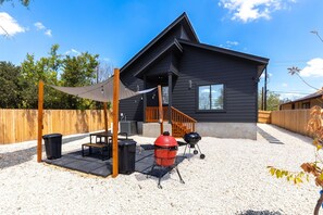 Ein modernes Haus mit überdachter Terrasse, Grill und Holzzaun.