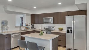 A modern kitchen with a central island, stainless steel appliances, and a water dispenser. - Urban Desert Home (Phoenix)
