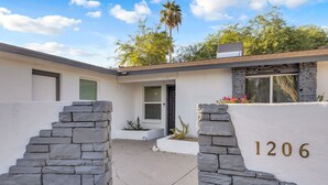 A modern house with a stone facade, a number '1206' on the wall, and a small garden area. - Urban Desert Home (Phoenix)