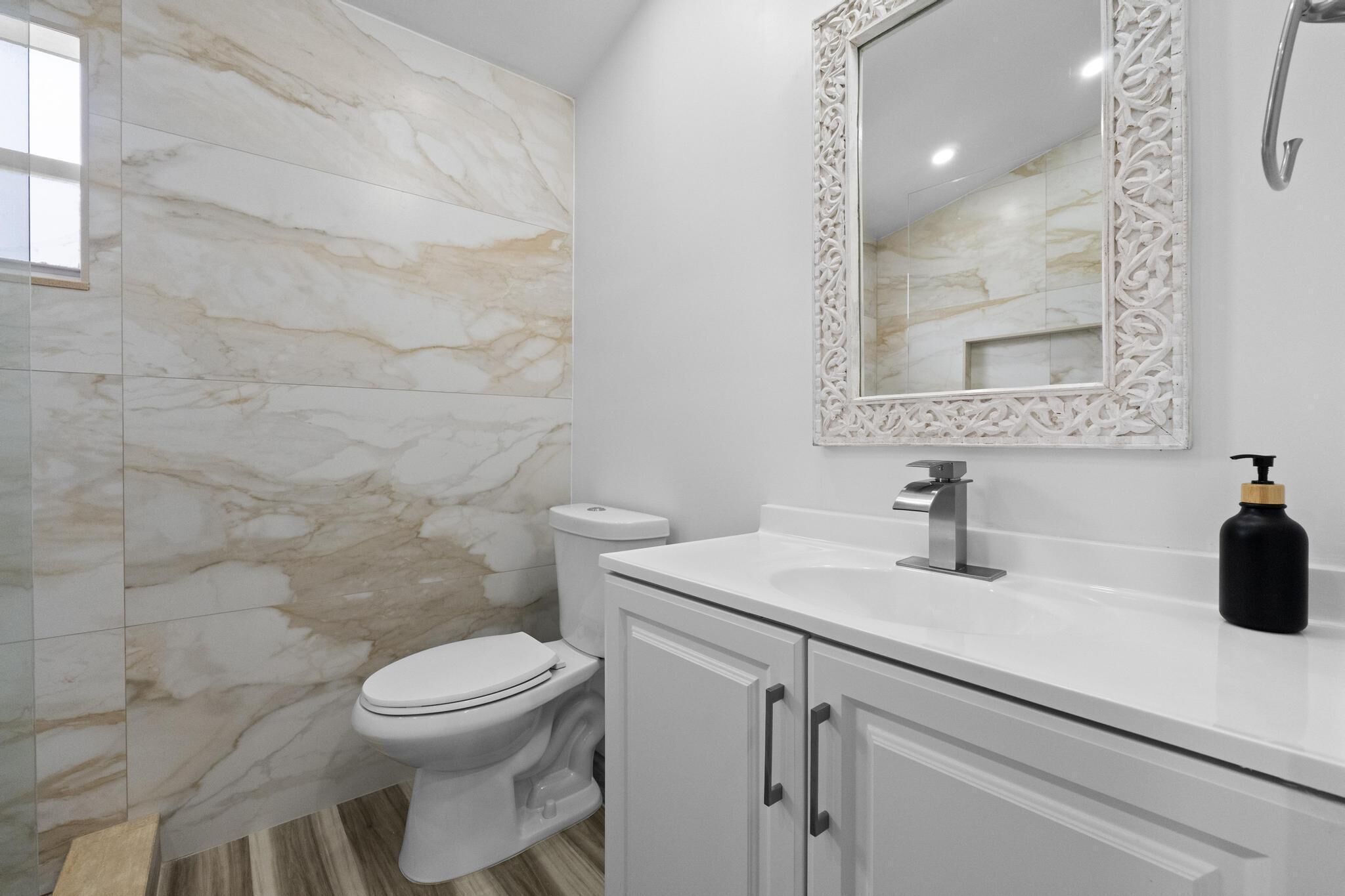 A bathroom with a toilet, a sink, and a mirror.