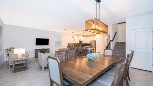 A modern dining area with a wooden table, chairs, and a hanging light fixture. - 9056SH: Meticulous 8 bed in The Retreat at ChampionsGate with No rear neighbors (Davenport)