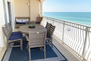 A balcony with a round table and chairs, a view of the ocean, and a patterned floor. - Luxury Direct Beachfront 3-bedroom Pet-Friendly Gated Condo in Redington Shores (Redington Shores)