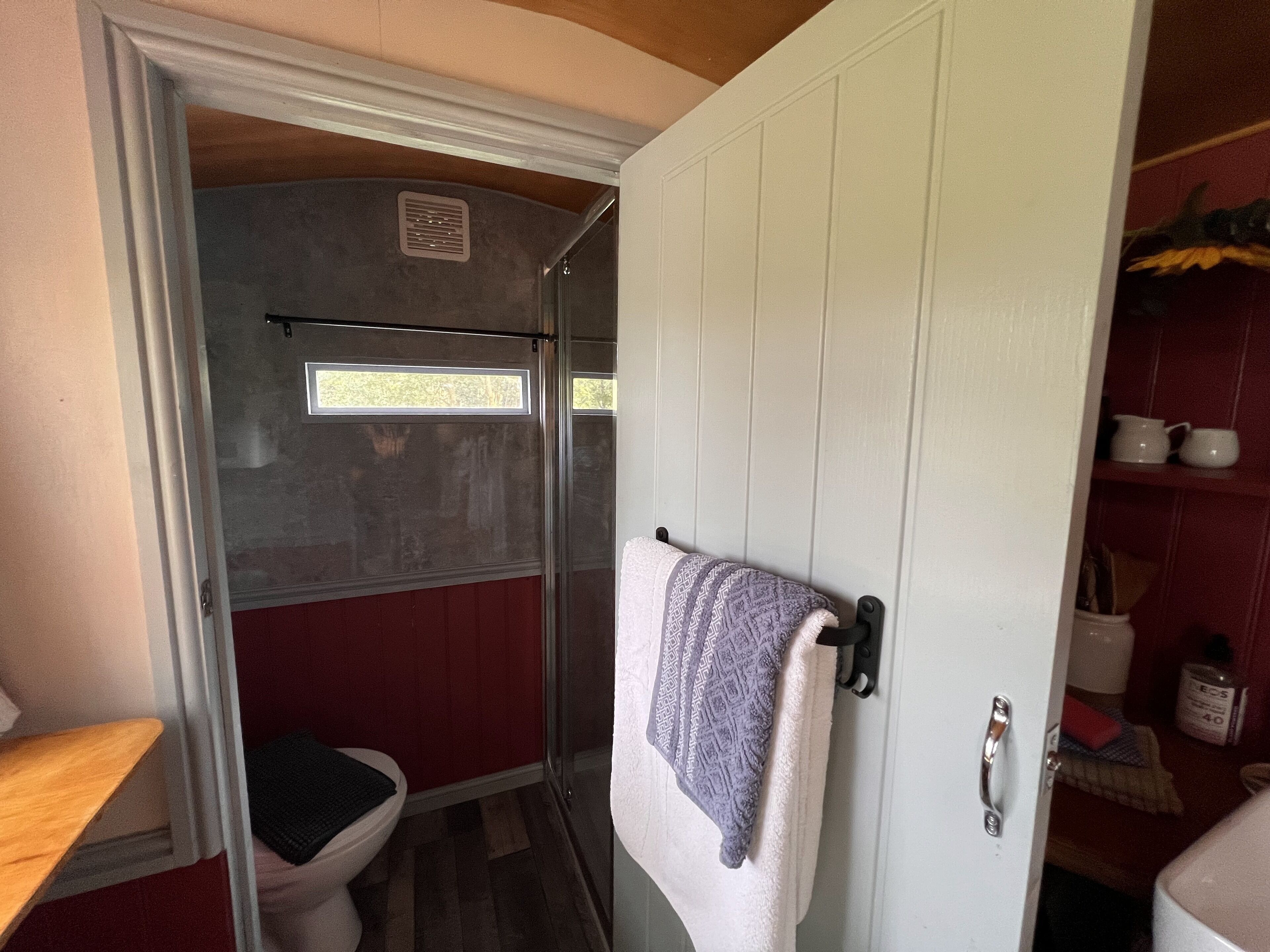 A compact bathroom with a shower, toilet, and a towel rack.