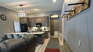 A modern kitchen with dark cabinets, a central island, and a red rug leading to a dining area. - Big Chip - 1 is in the heart of the Chippewa Flowage 20 minutes from Hayward, WI (Hayward)