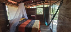 Une chambre avec un lit, une table de chevet et une fenêtre donnant sur des arbres.