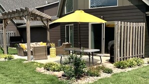 A modern house with a covered patio, a pergola, and outdoor furniture.