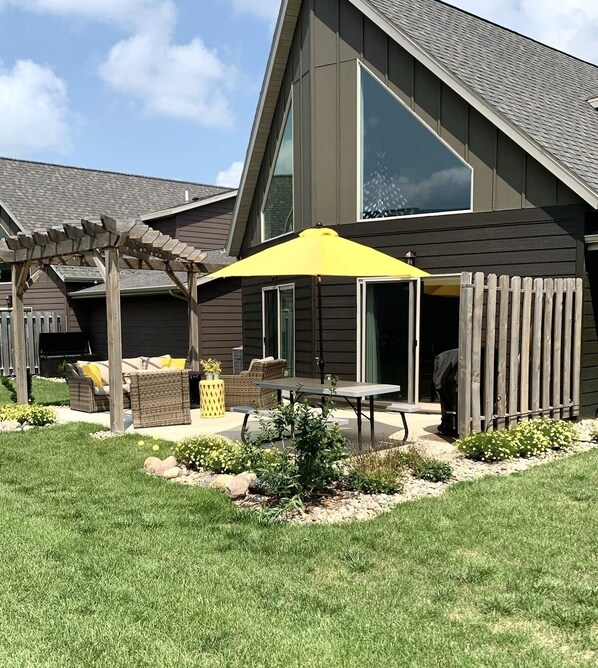 A modern house with a covered patio, a pergola, and outdoor furniture.