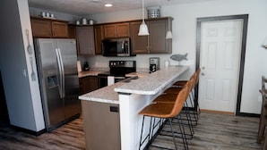 A modern kitchen with wooden cabinets, stainless steel appliances, and a granite countertop.