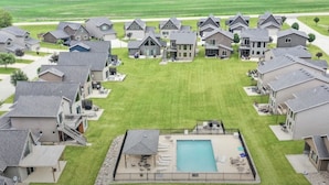 A residential area with multiple houses, a central swimming pool, and a well-maintained lawn.