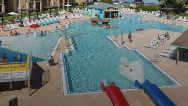 A swimming pool area with multiple pools, lounge chairs, and a water slide.