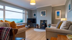A cozy living room with a fireplace, a television, and a view of the sea. - Valley View by Interhome (Mevagissey)