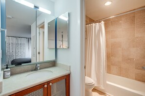 Bathroom features a large mirror, sink, shower curtain, and bathtub.