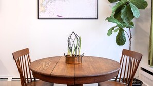 Una mesa de madera redonda con dos sillas, una planta en maceta y un mapa enmarcado en la pared.