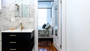 Un baño moderno con lavamanos de mármol, cabina de ducha de vidrio y vestidor.