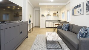 Una sala de estar moderna con un sofá gris, una mesa de centro de mármol y un televisor de pantalla plana sobre un mueble.