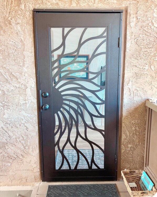 A door with a tree-like design, a doorknob, and a mat at the entrance. - Best 2BR Oceanview on property! Modern, luxury unit. Whales, Beach, Pool, AC! (Kihei)