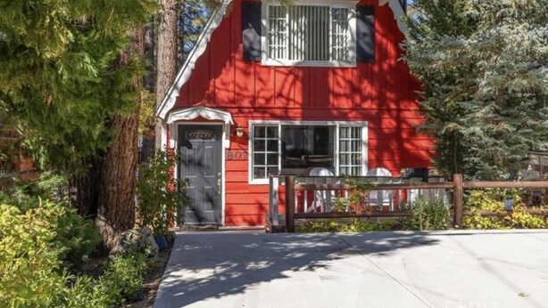 Une maison en bois rouge avec une porte d’entrée, des fenêtres et un petit porche.