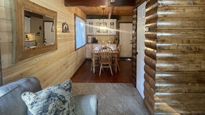 L’intérieur d’une cabane en rondins, avec un canapé, une table à manger et un coin cuisine.