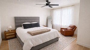 A bedroom with a bed, nightstand, chair, and ceiling fan. - Brand new apartment, sleeps 10, IDEAL location in Utah county. High end finishes (Lindon)