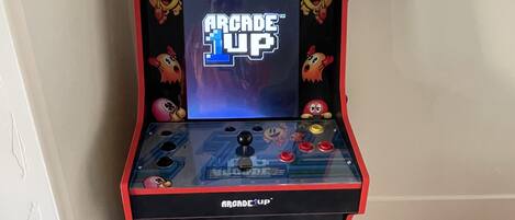 En retro arkademaskine med titlen "Arcade 1UP" og en karakter ved navn "Pachy" på skærmen.