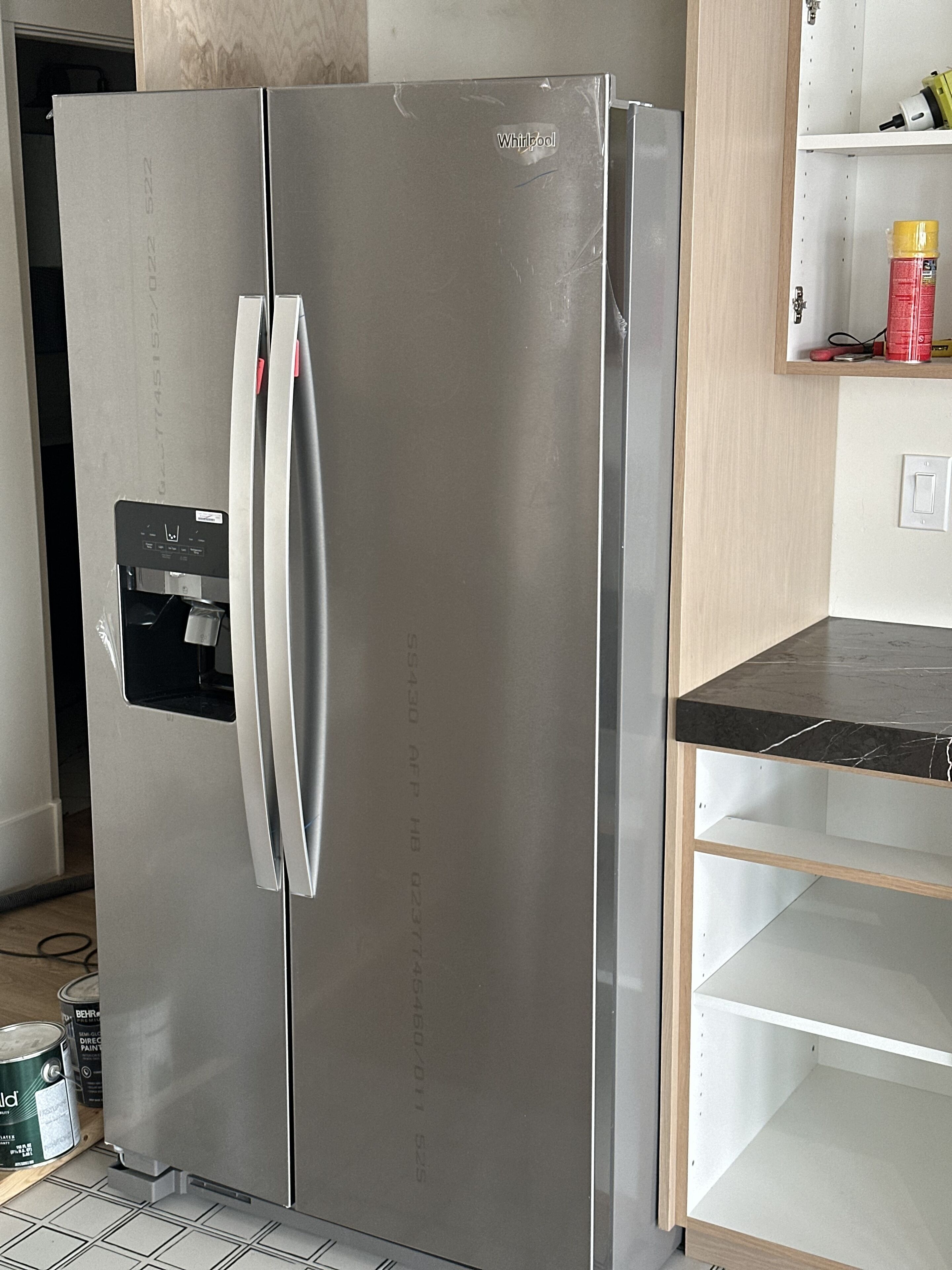 A stainless steel refrigerator with a freezer compartment on the left, a control panel on the door, and a black countertop to the right.