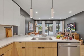 A modern kitchen with a central island, pendant lighting, and a view to the outside.