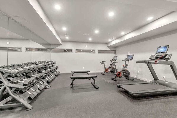 A gym with weight benches, treadmills, and stationary bikes.