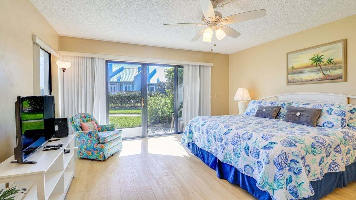 A bedroom with a bed, a TV, a sofa, and a painting.