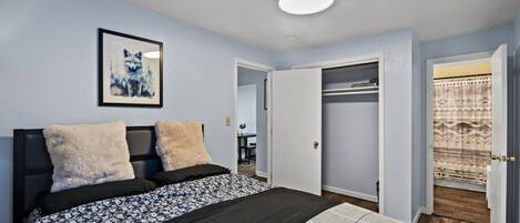 A bedroom with a bed, a framed artwork of a fox, a closet, and a patterned rug.