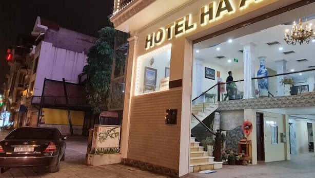 Entrada de un hotel con una escalera que conduce al piso superior, un candelabro y un letrero que dice "HOTEL HAY".