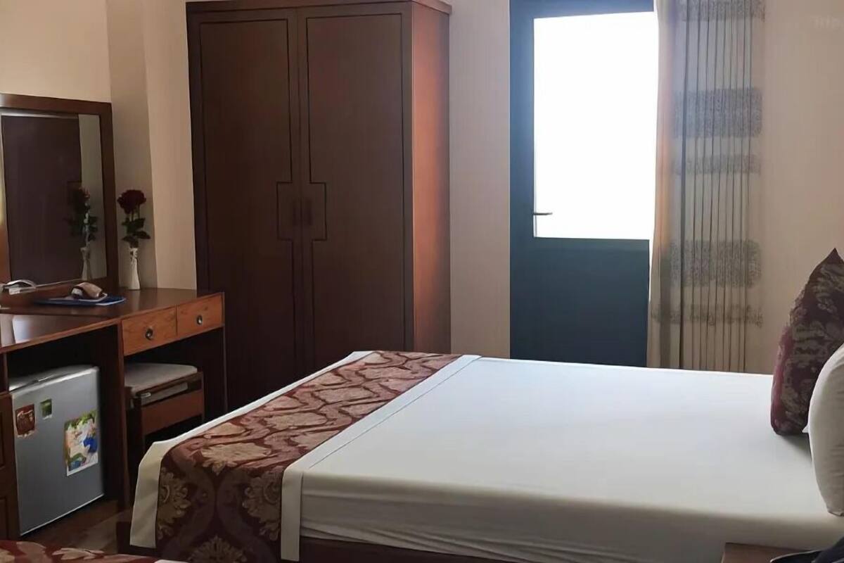Een slaapkamer met een bed, een dressoir, een spiegel en een kledingkast.