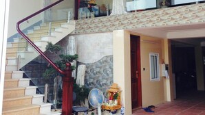 Un vestíbulo amplio con una imponente escalera, un jarrón grande y un ventilador.