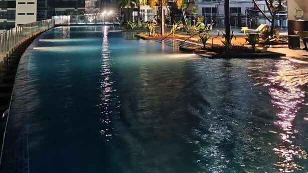 A nighttime view of a swimming pool area with a modern building in the background. - condominium rentals at Mactan Newtown (Lapu-Lapu)