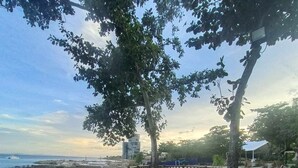 An outdoor deck with tables and chairs, overlooking a body of water and a distant cityscape. - condominium rentals at Mactan Newtown (Lapu-Lapu)