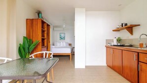 A compact hotel room with a bed, a small kitchenette, a dining area with a table and chairs, and a wooden cabinet. - Great location, walking distance to the beach -E (Puntarenas)