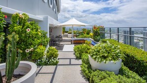 A rooftop terrace with outdoor seating, a view of the city, and a large white sign.