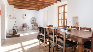 Un comedor con una mesa y sillas de madera, un reloj en la pared y una ventana que deja entrar luz natural.