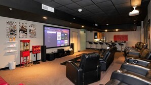 Un cine en casa con una pantalla grande, varios altavoces y sillones de cuero reclinables.