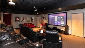 Una sala de cine en casa con una pantalla grande, varias opciones de asientos y un proyector.