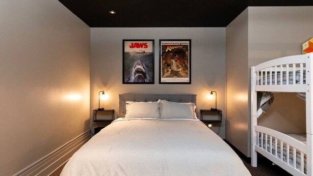 Habitación de hotel con una cama grande, dos carteles en la pared, una cama litera blanca y lámparas de noche.